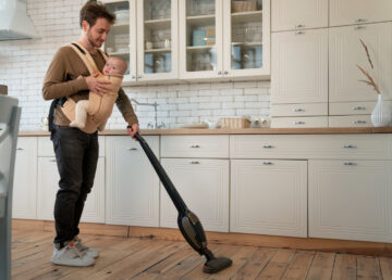Ojciec z dzieckiem na rękach sprzątający dom